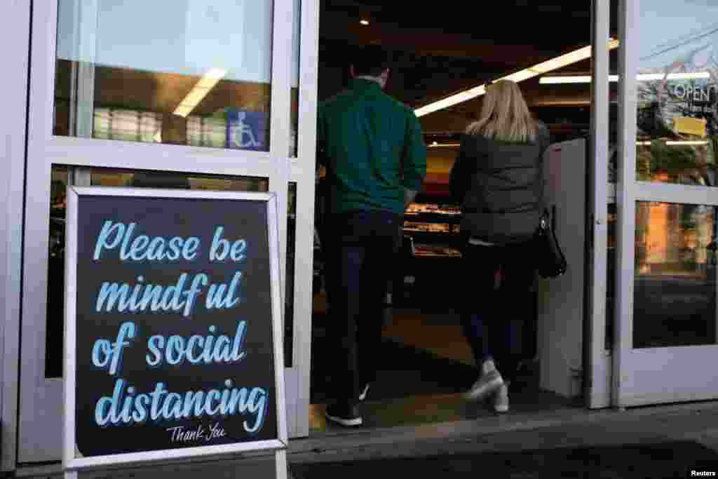 Shoppers enter a grocery store near a sign requesting social distancing, following reports of coronavirus cases in the area in Seattle, Washington, March 17, 2020.
