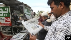 FILE - People read newspapers carrying headlines about India Pakistan tensions, in Karachi, Pakistan, Feb. 28, 2019.