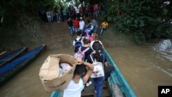 Venezolanos desembarcan un bote en el río Arauca, la frontera natural entre Venezuela y Colombia, cuando llegan a Arauquita, Colombia. Marzo 26, 2021.