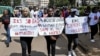 FILE - Protesters carry banners and chant slogans as they march through Eldoret, western Kenya, , to demonstrate against the murder of women in Kenya, on Sept. 13, 2024.