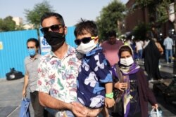 FILE - People wearing protective face masks walk in a street, following the outbreak of the coronavirus disease (COVID-19), in Tehran, Iran, June 28, 2020.
