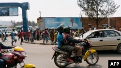 FILE - A passenger rides on a moto-taxi in Kigali, Rwanda, July 30, 2017. Rwanda is introducing electric motorcycles, with more than 600 being built for use in the country.