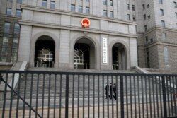 FILE - Policemen wearing face masks patrol at the compound of No. 2 Intermediate People's Court in Beijing on March 22, 2021, the day the trial of Canadian Michael Kovrig took place.