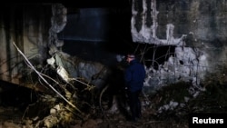 A man stands near the damaged canal in northern Kosovo supplying water to two coal-fired power plants that generate nearly all of the country's electricity, in Varage, Kosovo, Nov. 30, 2024. 