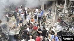 A crowd gathers in front of a building and car damaged after a bomb explosion in the Mezzeh 86 area in Damascus, in this handout photograph released by Syria's national news agency SANA, November 5, 2012. 