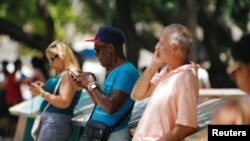 FILE - Cubans check their phones at an internet hotspot in Havana, Cuba, Aug. 10, 2018. 