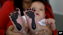In this May 2, 2019 file photo, Arelys Pulido holds her two-month-old daughter Zuleidys after she had her feet prints taken for her birth certificate at the Erazmo Meoz hospital in Cucuta, on Colombia's border with Venezuela.