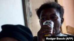 Une femme boit une bière dans une "shebeen", une taverne illégale en Afrique du Sud.