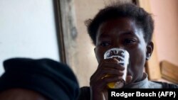 Une femme boit une bière dans un bar illégal à 15 km du de Cape Town le 10 février 2012.