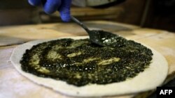 FILE - A baker spreads a mixture on a disc of dough to make a traditional Lebanese manoushe flatbread, at a bakery in Tabarja north of Beirut on December 6, 2023. UNESCO said it was adding Lebanon's iconic manoushe to its list of intangible cultural heritage.