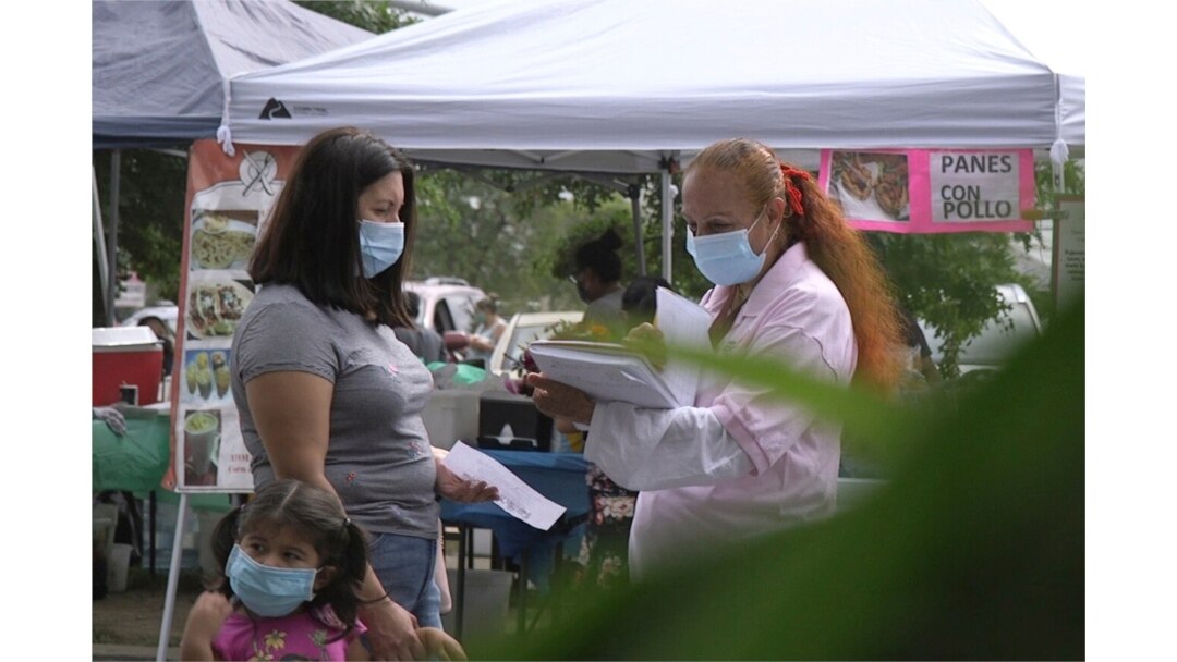 FILE - A 'promotora' (health promoter) from CASA, a Hispanic advocacy group, tries to enroll Latinos as volunteers to test a potential COVID-19 vaccine, at a farmers market in Takoma Park, Md., on Sept. 9, 2020.