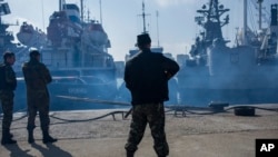 FILE — Men in unmarked uniforms stand guard during the seizure of the Ukrainian corvette Khmelnitsky in Sevastopol, Crimea, March 20, 2014.