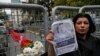 Sahar Zeki, an activist and a friend of slain Saudi writer Jamal Khashoggi, holds a picture of him, after attaching a bouquet of flowers, at the barriers blocking the road leading to the Saudi Arabia's consulate in Istanbul, Tuesday, Oct. 23, 2018. Saudi officials murdered journalist Jamal Khashoggi in their Istanbul consulate after plotting his death for days, Turkey's president said Tuesday, contradicting Saudi Arabia's explanation that the writer was accidentally killed. He demanded that the kingdom reveal the identities of all involved, regardless of rank.