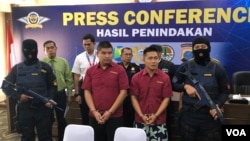 Dua tersangka PF (merah kiri) dan XY (merah kanan) WN China yang melakukan percobaan penyelundupan sisik trenggiling di Bandara Internasional Kualanamu, Deli Serdang, Sumatera Utara. Senin (29/4). (VOA/Anugrah Andriansyah)