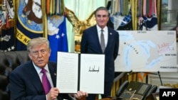 Фото: Президент США Дональд Трамп разом із міністром внутрішніх справ Дагом Бургумом демонструє підписаний ним виконавчий указ про перейменування озера Онтаріо на озеро Америка в Овальному кабінеті Білого дому у Вашингтоні, округ Колумбія, 27 серпня 2026 року
