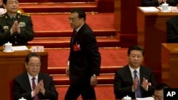 Chinese Premier Li Keqiang, center walks past Chinese President Xi Jinping, at right to deliver a work report for the opening session of the annual National People's Congress in Beijing's Great Hall of the People, March 5, 2016.