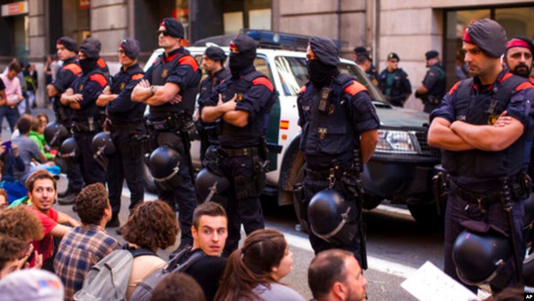 Polisi Catalonia, Catalan Mossos d'Esquadra, melindungi kendaraan yang yang mengangkut petugas pengawal warga sipil saat berlangsungnya aksi unjuk rasa di Barcelona, Spanyol, 20 September 2017. (Foto: dok). 
