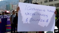 ARCHIVO - Un comerciante sostiene un cartel con un mensaje que dice en español: "¡Gobierno actual, necesitamos dólares!". Durante una protesta en La Paz, Bolivia, el viernes 17 de mayo de 2024.