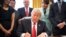 U.S. President Donald Trump signs an executive order cutting regulations, accompanied by small business leaders at the Oval Office of the White House in Washington, Jan. 30, 2017. 