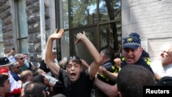 На фото: протестувальники у Тбілісі штурмують офіс ЛГБТ організації