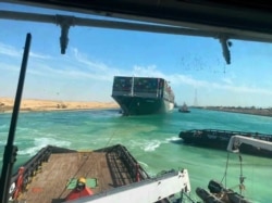 In this photo released by Suez Canal Authority, the Ever Given, a Panama-flagged cargo ship is accompanied by Suez Canal tugboats as it moves in the Suez Canal, Egypt, March 29, 2021.