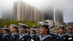 Chinese sailors sit before the start of a concert featuring Chinese and foreign military bands in Qingdao, Monday, April 22, 2019. 