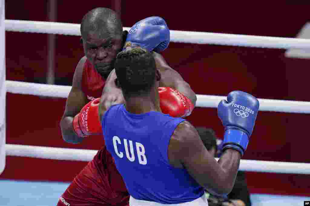 Kenya&#39;s Elly Ajowi Ochola, left, exchanges punches with Cuba&#39;s Julio la Cruz during their men&#39;s heavyweight 91-kg boxing match at the 2020 Summer Olympics, Tuesday, July 27, 2021, in Tokyo, Japan. (AP Photo/Frank Franklin II)