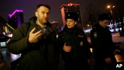 Russian opposition activist Alexei Navalny, left, is briefly detained by police officers after defying his house arrest to speak on Radio Ekho Moskvy in Moscow, Jan. 14, 2015.