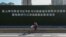 一名戴著口罩的婦女從武漢街頭一幅宣傳習近平湖北講話的大標語前騎車而過。 （2020年3月10日）