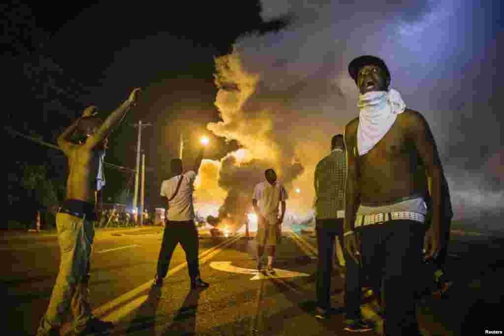 Demonstrators react to tear gas fired by police during ongoing protests in reaction to the shooting of teenager Michael Brown, in Ferguson, Missouri, August 18, 2014. REUTERS/Lucas Jackson