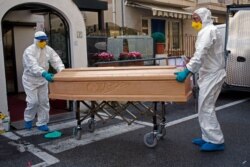 Medical staff wearing protective suits carry the coffin containing the body of Assunta Pastore, 87, after she passed away in her room at the Garden hotel in Laigueglia, northwest Italy, Liguria region, March 1, 2020.