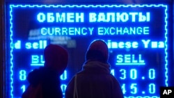 FILE - Women look at a screen showing the exchange rate at a money exchange office in St. Petersburg, Russia on March 1, 2022. (AP Photo/Dmitri Lovetsky, File)