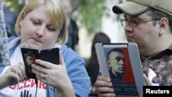 Opposition activists use electronic devices pictured with portraits of prominent anti-corruption blogger Alexei Navalny during a four day-long protest in a boulevard in central Moscow, May 10, 2012.