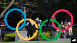 Orang-orang mengambil gambar cincin Olimpiade yang dipasang oleh Museum Olimpiade Jepang di Tokyo pada hari Jumat, 19 Maret 2021. (Foto: AP/Hiro Komae)