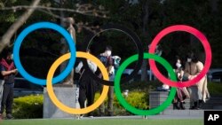 Orang-orang mengambil gambar cincin Olimpiade yang dipasang oleh Museum Olimpiade Jepang di Tokyo pada hari Jumat, 19 Maret 2021. (Foto: AP/Hiro Komae)