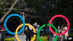 Orang-orang mengambil gambar logi Olimpiade yang dipasang oleh Museum Olimpiade Jepang di Tokyo pada hari Jumat, 19 Maret 2021. (Foto: AP/Hiro Komae)