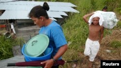 Una mujer y su hijo cargan sus pertenencias por su barrio pobre de Tegucigalpa el 27 de febrero de 2006.