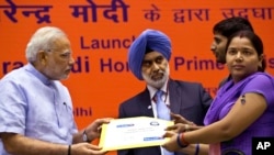 Indian Prime Minister Narendra Modi hands over a banking kit to an unidentified woman at the launch of a campaign aimed at opening millions of accounts for poor Indians in New Delhi, India, Aug. 28, 2014.