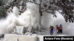 People are seen on a road blanketed with volcanic ash from the erupting Mount Semeru in Lumajang, East Java Province, Indonesia.