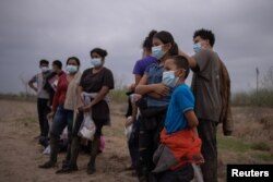 Aproximadamente una docena de menores no acompañados de América Central que buscan asilo son separados de otros migrantes por agentes de la Patrulla Fronteriza de EE. UU. tras cruzar el río Grande, el 14 de marzo de 2021.