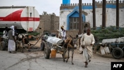 FILE - People refill donkey-drawn water tanks during a water crisis in Port Sudan on April 9, 2024.