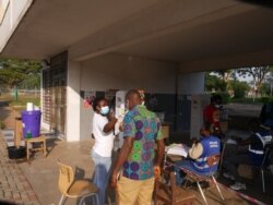 Voters have their temperature checked before casting their ballots, in Accra, Dec. 7, 2020. (Stacey Knott/VOA)