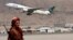 FILE - A Taliban fighter stands guard as a Pakistan International Airlines plane, the first commercial international flight to land after the Taliban retook power, takes off at the airport in Kabul on Sept. 13, 2021.