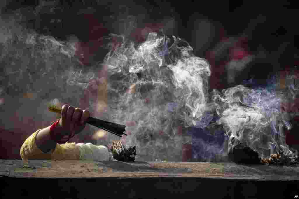 A Nepalese woman lights incense sticks and offers prayers at the Pashupatinath temple during Teej festival celebrations in Kathmandu, Nepal.