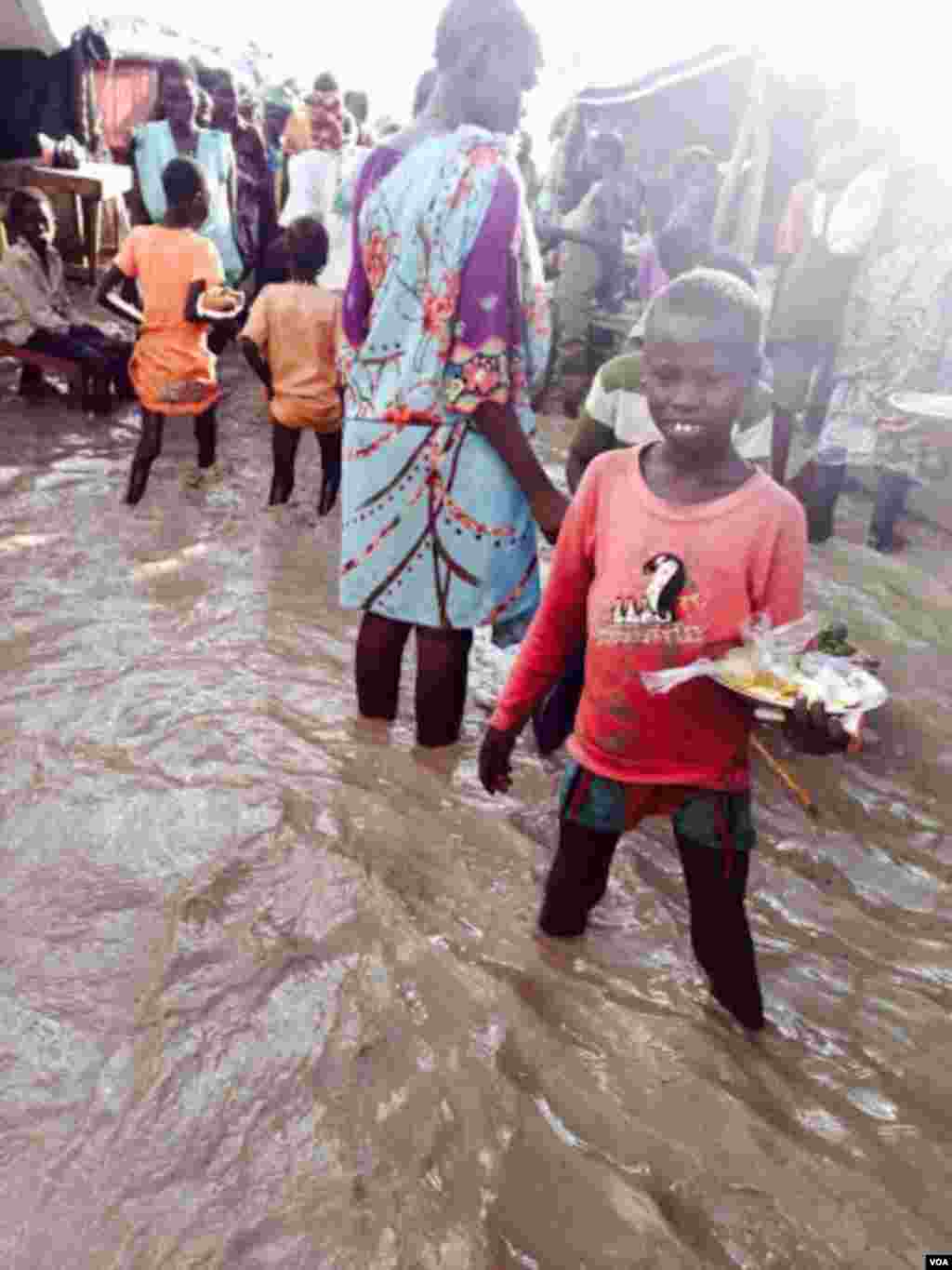 A child stands in floodwaters at a camp for people displaced by violence, Bentiu, South Sudan (G. Joselow/VOA).