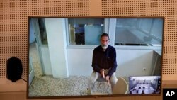 John McAfee, creator of McAfee antivirus software is seen on a screen while testifying via video during an extradition hearing in Madrid, Spain, on June 15, 2021. McAfee has been found dead on June 24, 2021, in his jail cell in an apparent suicide.