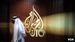 Seorang karyawan stasiun televisi Arab Al Jazeera berjalan melewati logo Al Jazeera di Doha, Qatar. FIFA memperpanjang hak siaran Al Jazeera hingga Piala Dunia 2022.