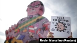 A demonstrator holds a banner reading, "Bolsonaro virus out," during a protest against the president in Brasilia on May 29, 2021.