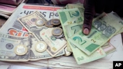 FILE - A man counts Zimbabwean dollar notes and coins and U.S. dollar notes on the streets of Harare, June 25, 2019. 