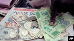 FILE - A man counts Zimbabwean dollar notes and coins and U.S. dollar notes on the streets of Harare, June 25, 2019. 